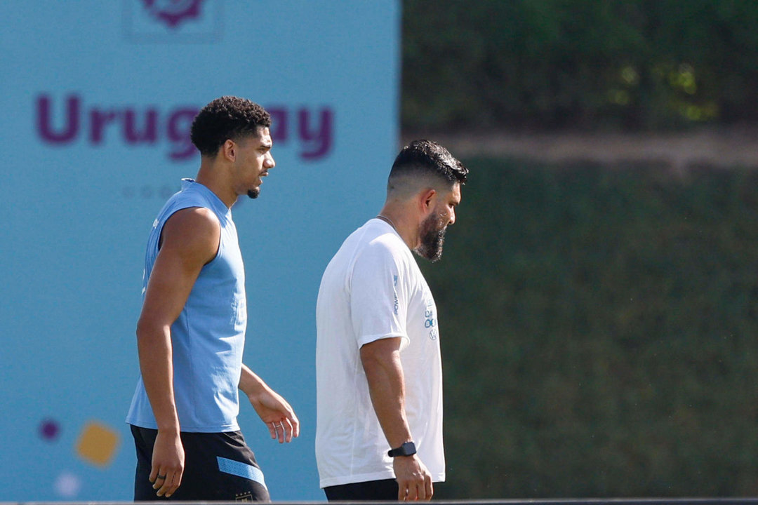 El defensa Ronald Araujo (izq) conversa con un preparador físico del FC Barcelona durante el entrenamiento de la selección uruguaya celebrado hoy en las instalaciones de Al Erssal, en Doha. EFE/ Rodrigo Jiménez