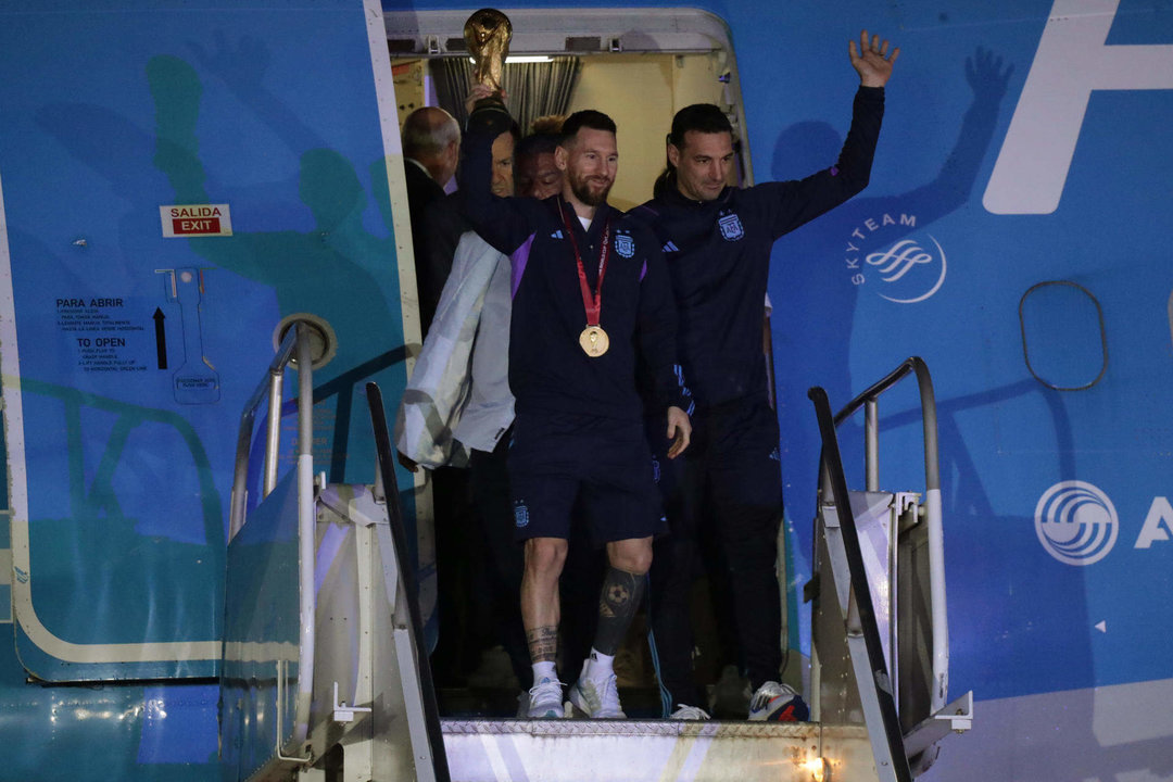 Lionel Messi de la selección argentina de fútbol saluda con el trofeo del Mundial de Fútbol Qatar 2022 junto al seleccionador Lionel Scaloni (d) a su llegada al Aeropuerto Internacional de Ezeiza a unos 22km de Buenos Aires (Argentina). EFE/ Raúl Martínez